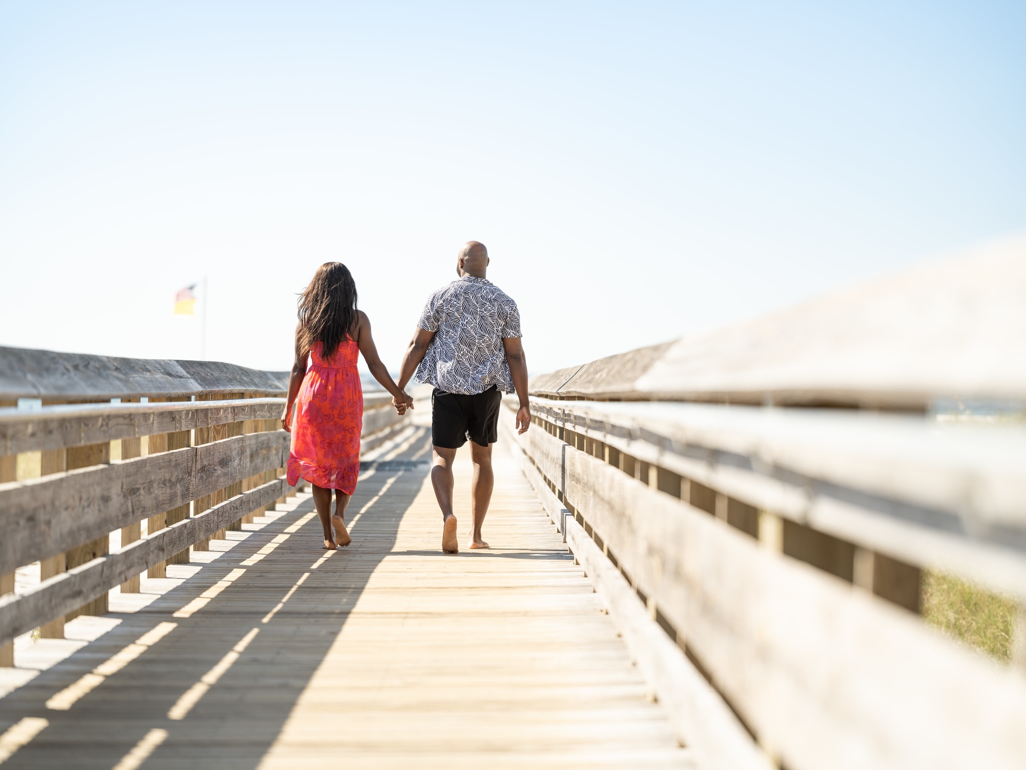 A couple walking toward the beach on a boardwalk