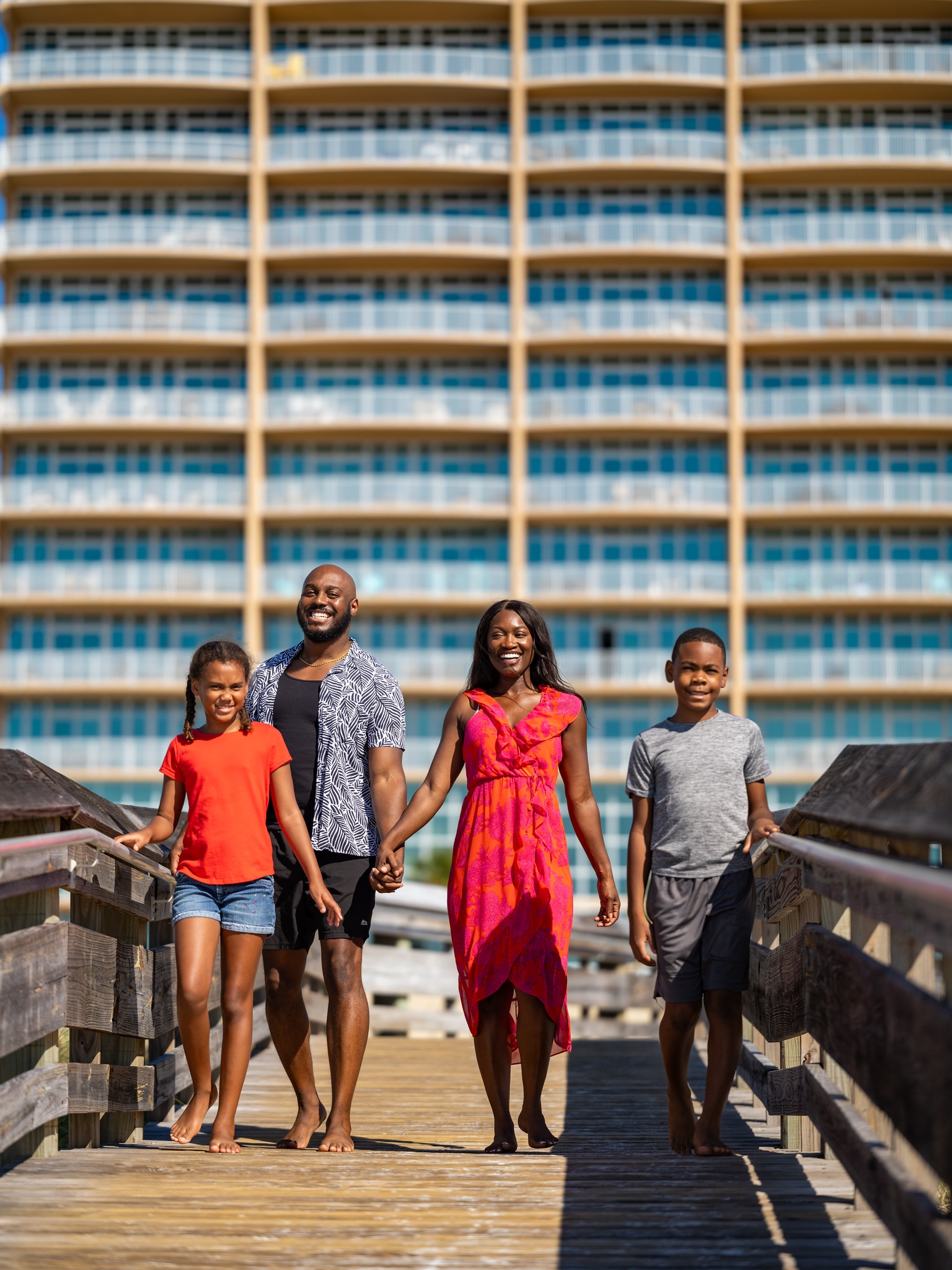 Family together on a beach boardwalk beside a condominium building