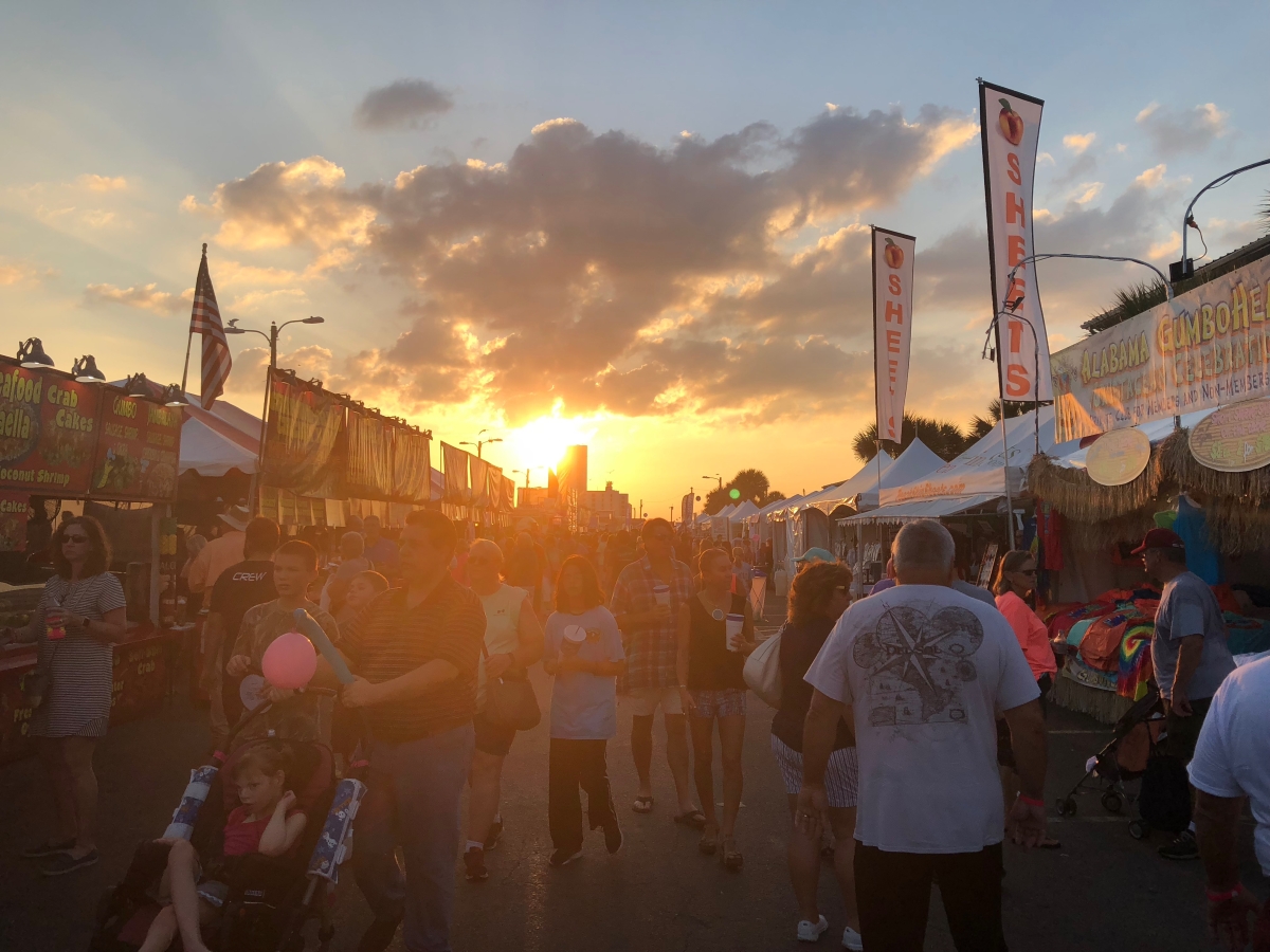 Festival visitors along a Gulf Shores street at sunset