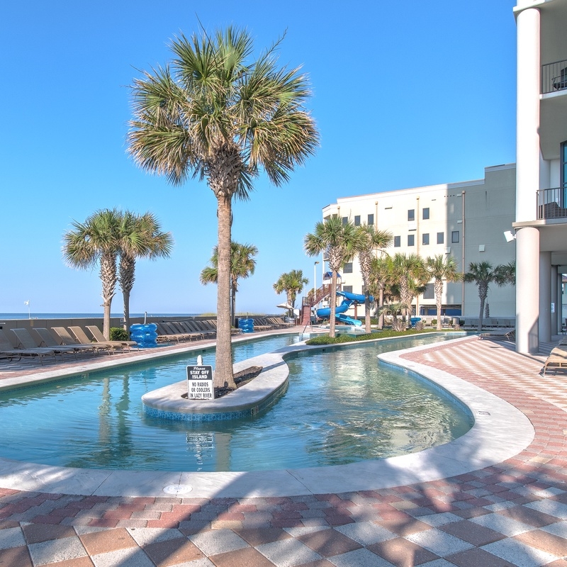 Beachfront lazy river with palm trees at The Oasis at Orange Beach